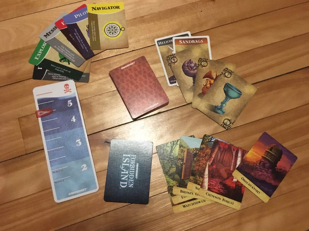 A top down view of the components of the game. Includes the tiles, flood counter, player cards, and card deck.